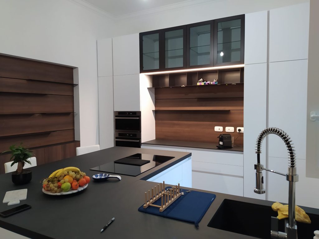 Cucina con top scuro, colonne bianche e boiserie in legno
