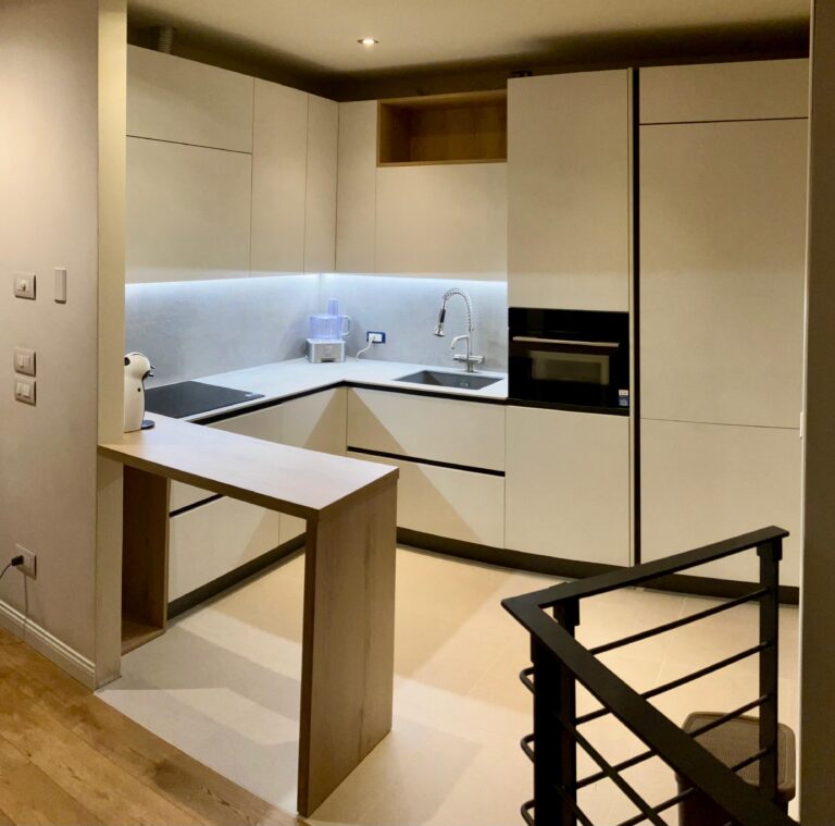Cucina open space con penisola in legno e colonne color crema