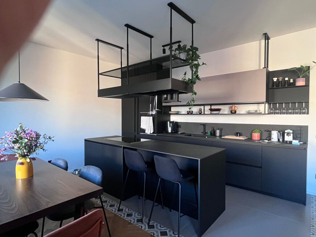 Cucina industrial con isola nera e cappa sospesa in metallo